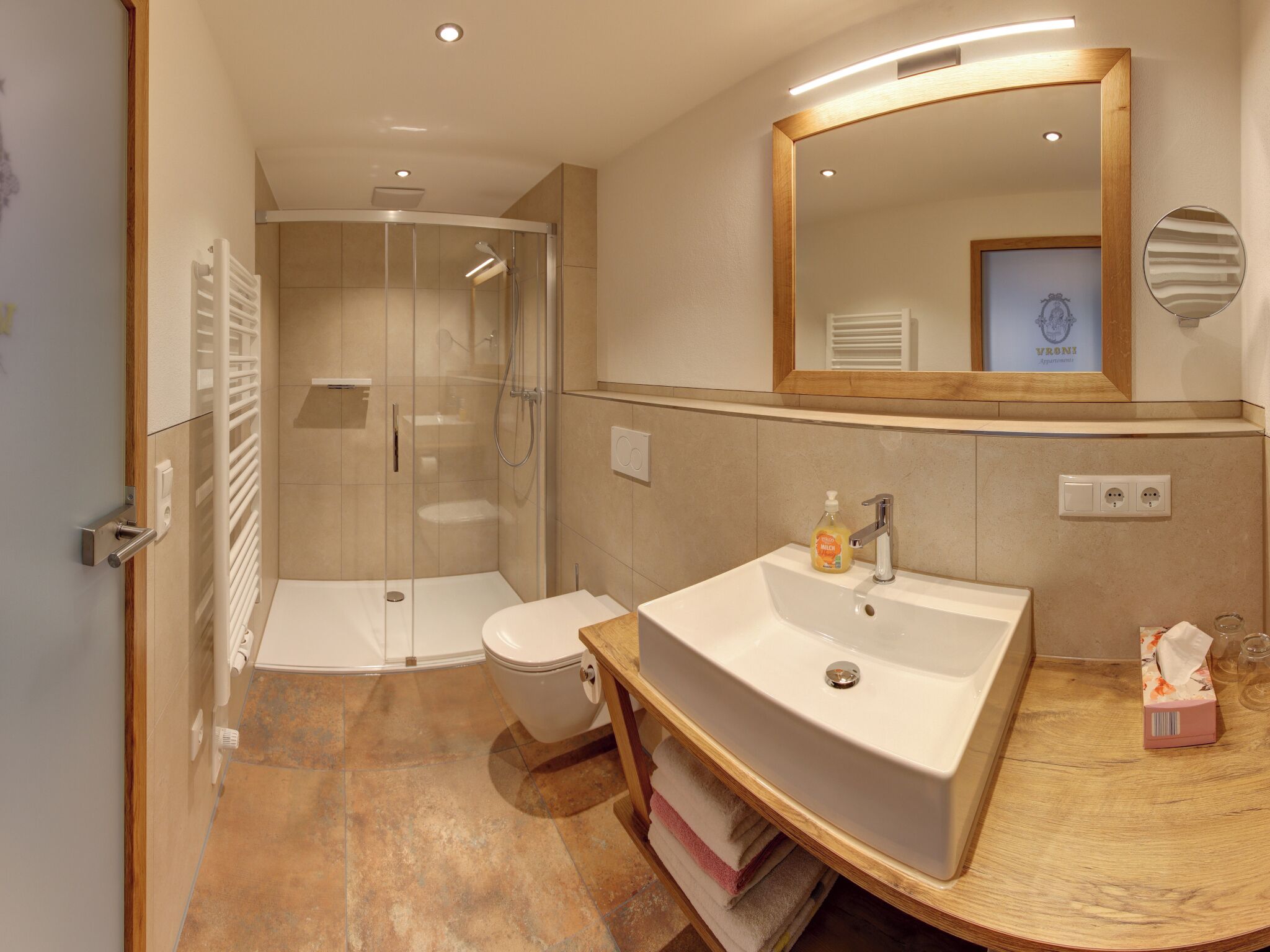 A modern bathroom with a glass-enclosed shower, a white sink, and a large mirror.