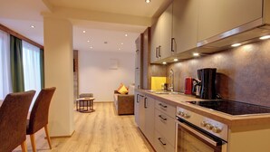 A modern kitchen with wooden flooring, a built-in oven, and a coffee maker. - Apartment 3 for 4 persons, 1 separate bedroom, balcony, 53 m² (Inzell)