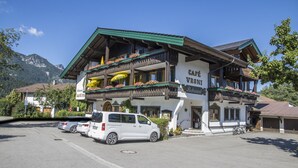 A traditional Alpine-style building with balconies, a sign reading "CAFÉ YRONI," and parked cars in front. - Apartment 3 for 4 persons, 1 separate bedroom, balcony, 53 m² (Inzell)