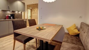 A modern dining area with a wooden table, chairs, and a hanging light fixture. - Apartment 3 for 4 persons, 1 separate bedroom, balcony, 53 m² (Inzell)