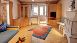 A cozy living room with wooden cabinets, a television, and a fireplace. - Apartment 4 for 2 persons, 1 separate bedroom, balcony, 58 m² (Inzell)
