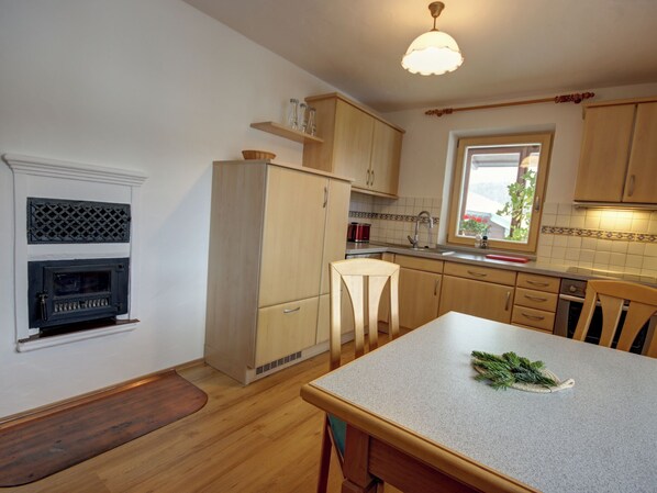 A kitchen with wooden cabinets, a built-in oven, a window with a view, and a dining area with a table and chairs.