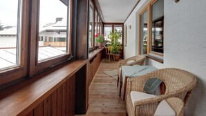 A wooden balcony with a table and chairs, potted plants, and a view of buildings. - Apartment 4 for 2 persons, 1 separate bedroom, balcony, 58 m² (Inzell)