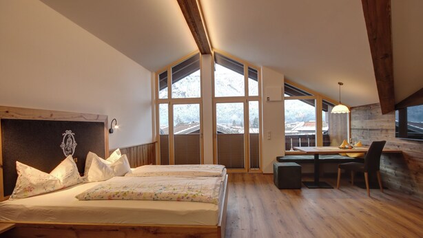 Un dormitorio con cama de madera, un escritorio y vistas a un paisaje nevado a través de amplios ventanales.