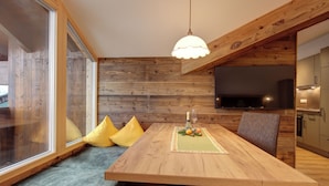 Comedor con mesa de madera, cojines amarillos y lámpara colgante.