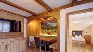 Une pièce chaleureuse avec un plafond en bois, un coin repas comprenant une table et des chaises, et un lit doté d’une tête de lit.