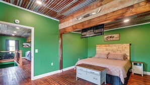 Un dormitorio con cabecera de madera, una cama con colcha color crema, una mesita de noche y un aparador.