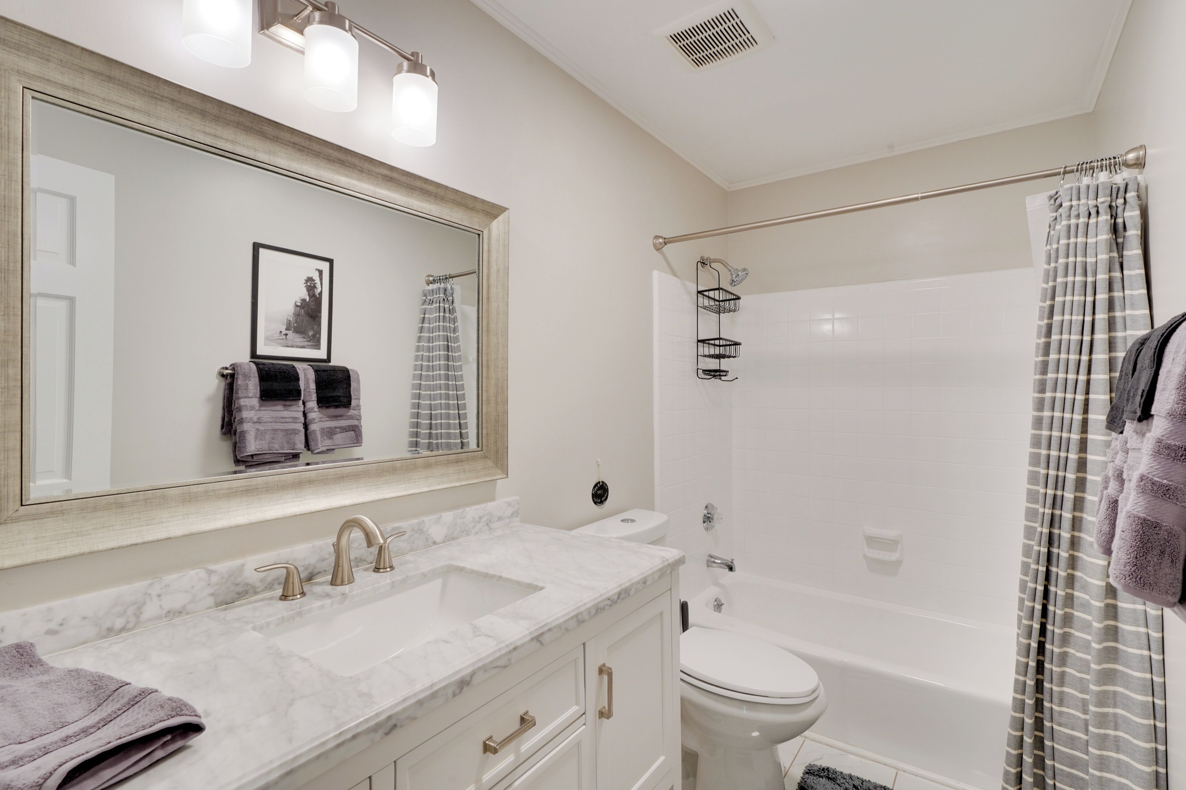 A bathroom with a large mirror, two sinks, a toilet, and a shower.