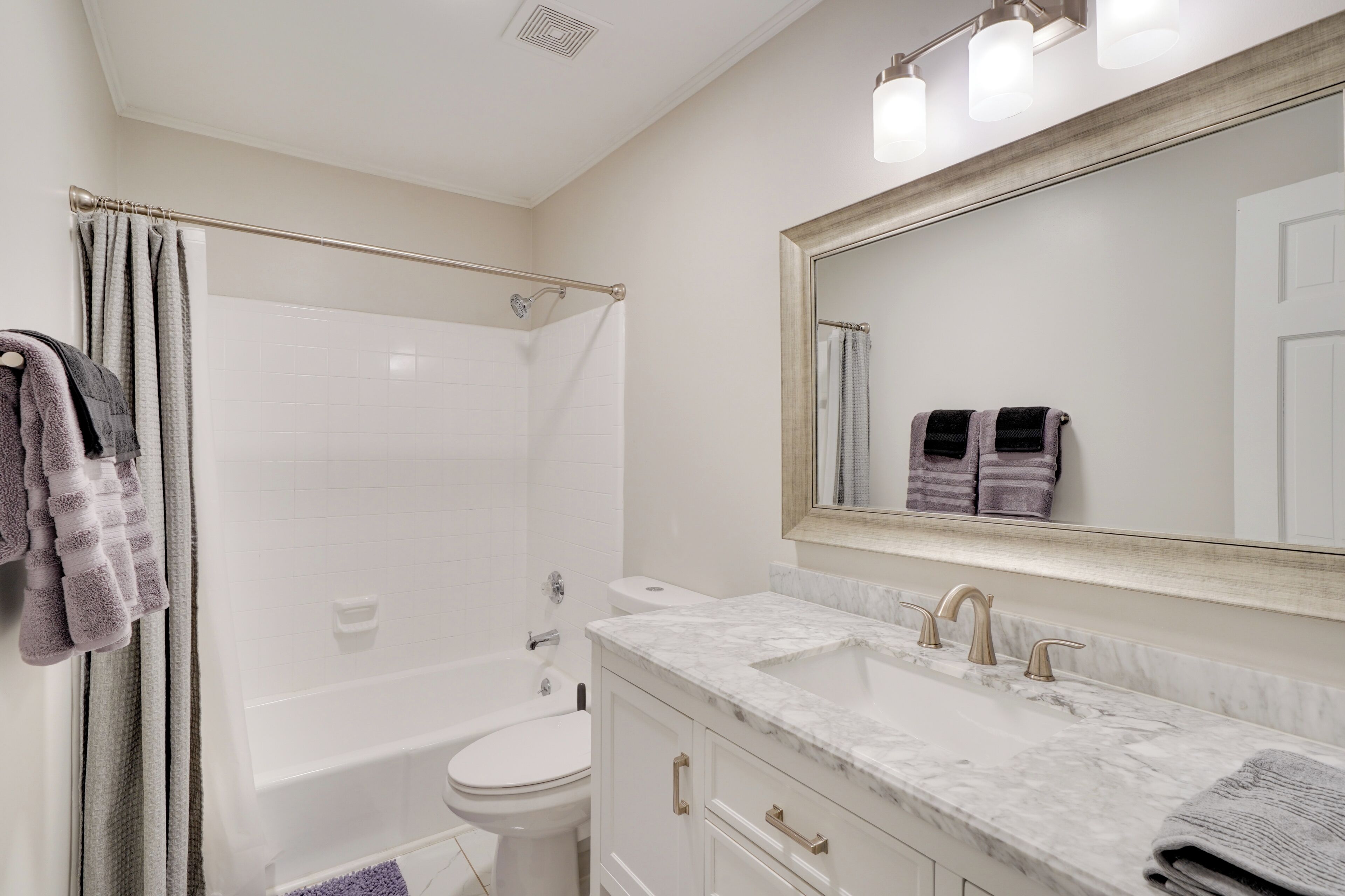 A bathroom with a bathtub, toilet, and vanity with a mirror.
