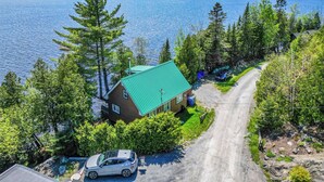 A house with a green roof, a driveway, and a car parked in front. - Havre du Huit (Adstock)