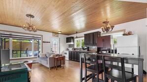 A spacious kitchen with wooden flooring, dark cabinets, and a central island with chairs. - Havre du Huit (Adstock)