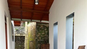 Un espace extérieur abrité, aménagé avec du mobilier en bois, un mur en pierre et un plafond en bois.