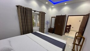 Une chambre à coucher avec un lit, une armoire, un miroir et un ventilateur.