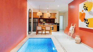 A modern kitchen with wooden cabinets, a dining area with a pool table, and a painting on the wall. - Exquisite 2 Bedroom Retreat Nestled In The Serene Pecatu (pecatu)