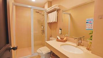 Une salle de bain avec une douche à parois de verre, des toilettes, un lavabo avec un miroir et un porte-serviettes.