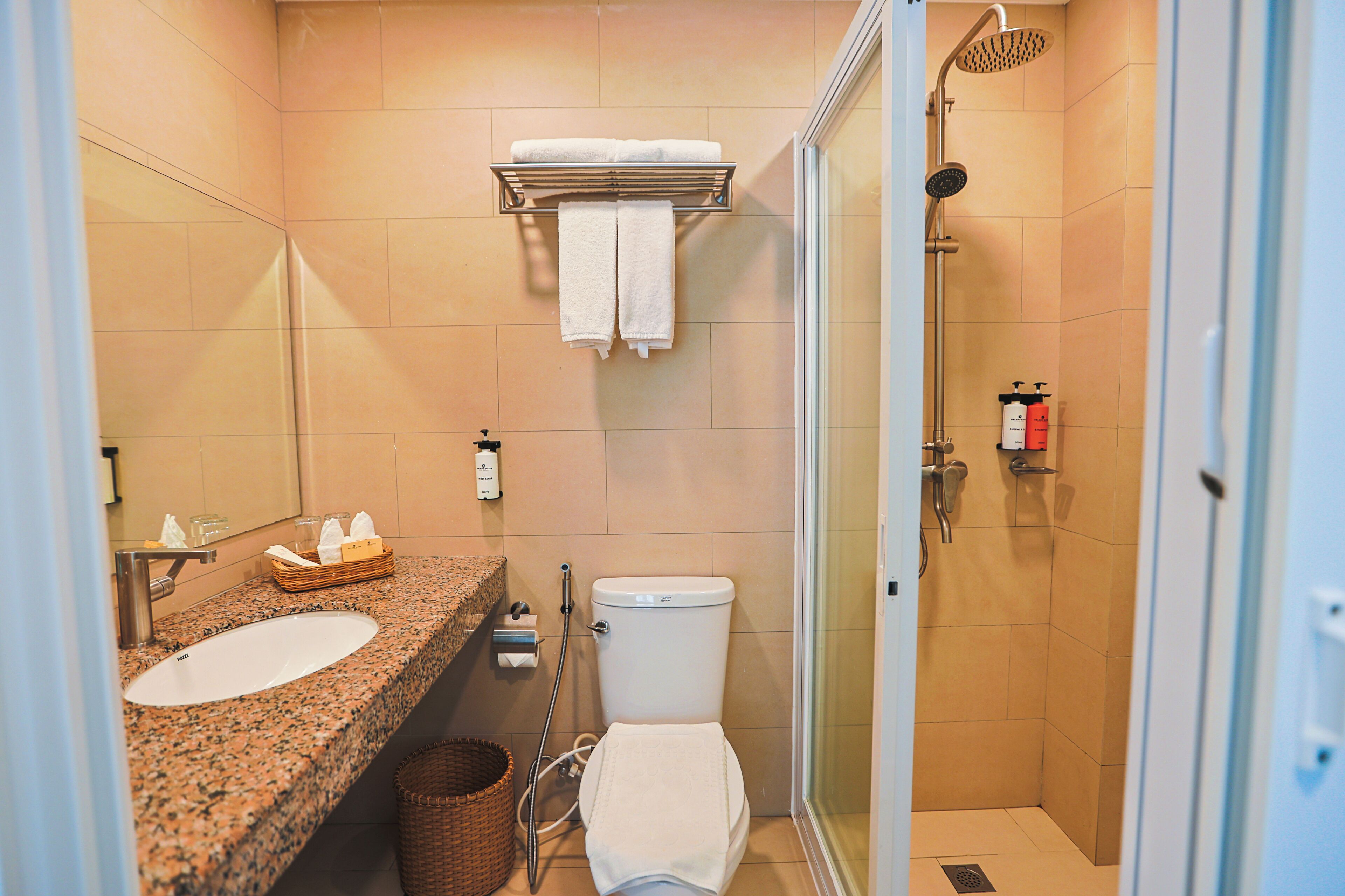 A bathroom with a granite sink, white toilet, and a glass-enclosed shower.