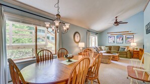 A spacious living room with a large wooden dining table, comfortable seating, and a ceiling fan. - Indoor Pool, Hot Tub, Storyland (Bartlett)
