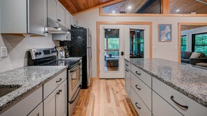A modern kitchen with granite countertops, stainless steel appliances, and wooden flooring. - Family-Friendly Chalet: Hot Tub, Games, Fire Pit (Jackson)