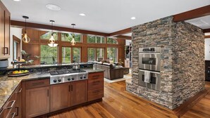 A modern kitchen with a large island, built-in appliances, and a stone accent wall.