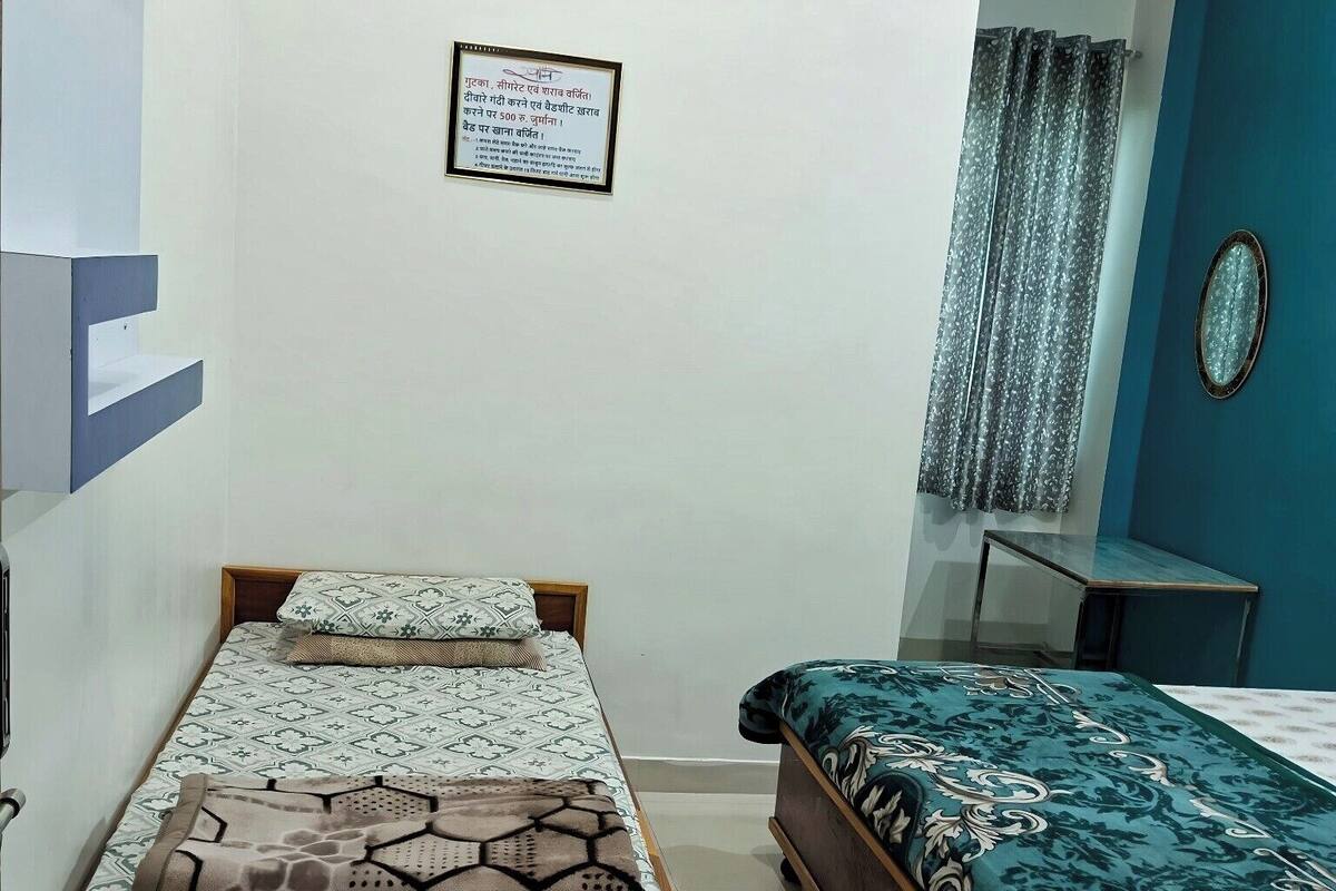 Een slaapkamer met twee bedden, een klein tafeltje, een spiegel en een lijst aan de muur.