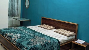 A bedroom with a large bed, a bedside table, a mirror, and a ceiling light. - Prem Bhawan Guset House (Danta Ramgarh)