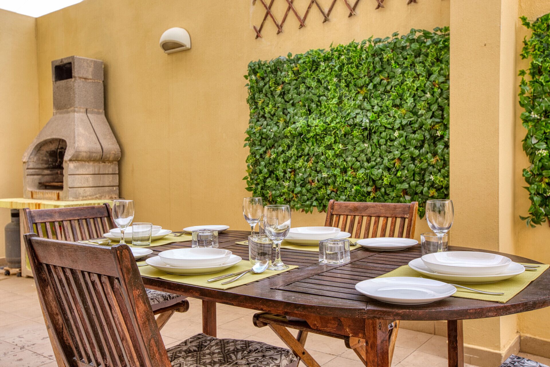 Une table à manger dressée avec des assiettes, des verres et des couverts, entourée de chaises.