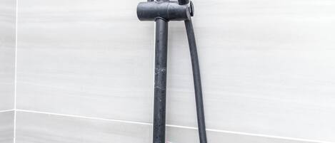 A shower with a handheld showerhead and a wall-mounted control valve.