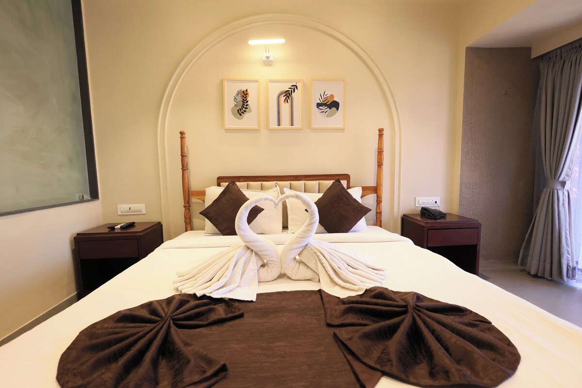 Een hotelkamer met een net opgemaakt bed, een houten hoofdbord en drie ingelijste kunstwerken aan de muur.
