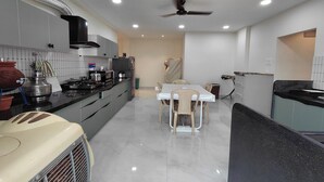 A modern kitchen with a dining area, featuring a stove, sink, and ceiling fan. - V & U Homestay Sadar (Nagpur)