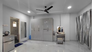 A modern bedroom with a bed, a wardrobe, a desk with a mirror, and a ceiling fan. - V & U Homestay Sadar (Nagpur)