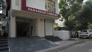 A building with a sign reading "PARASHAR COMPLEX" and a white car parked in front. - V & U Homestay Sadar (Nagpur)