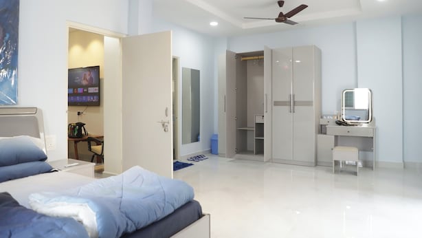 A modern bedroom with a bed, a desk, a wardrobe, and a ceiling fan. - V & U Homestay Sadar (Nagpur)