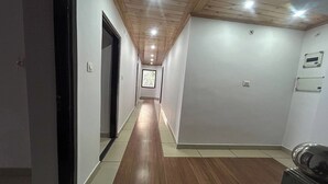 Un pasillo con suelo de madera y paredes blancas, que conduce a una puerta al final.
