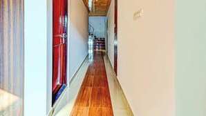 Un pasillo con techo de madera, puertas rojas y piso de baldosas.
