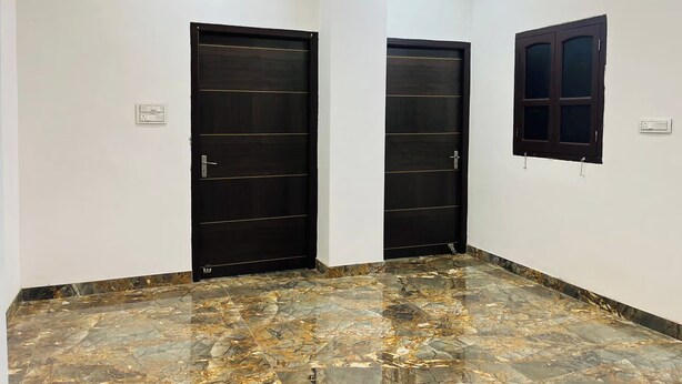 A room with two dark wooden doors, a window with a dark frame, and a marble-patterned floor. - Suriya Inn (Udaipur)
