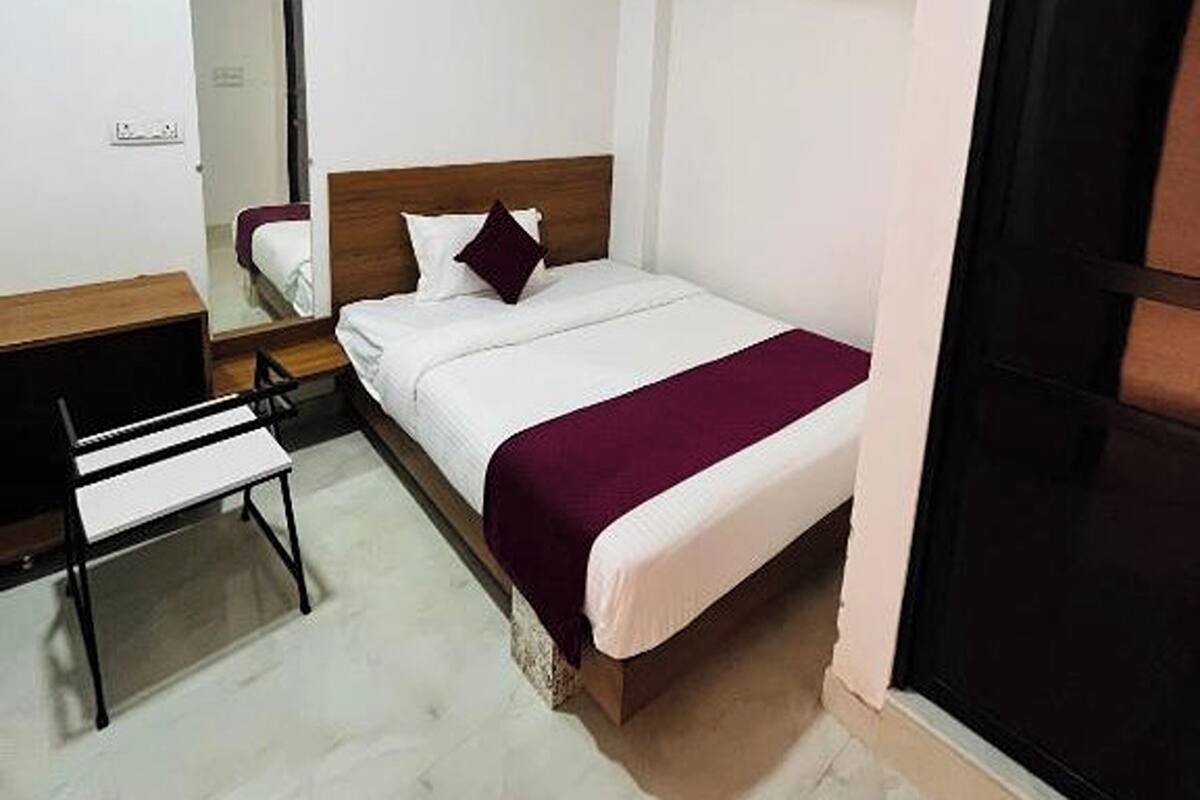A bedroom with a bed, a desk, and a mirror.