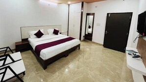 A modern bedroom with a bed, a desk, a wardrobe, and a door. - Suriya Inn (Udaipur)