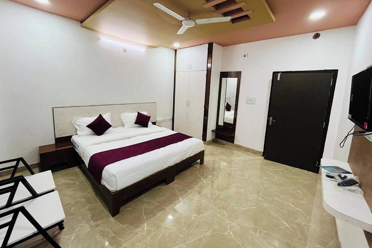 A modern bedroom with a bed, a desk, a wardrobe, and a door.