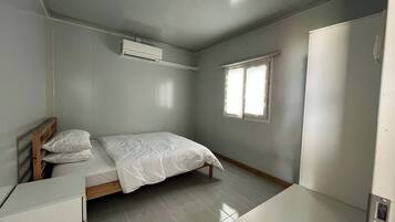 Un dormitorio con cama, escritorio, armario y ventana.
