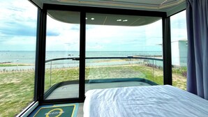 Ein modernes Hotelzimmer mit großem Fenster und Blick auf Strand und Meer.