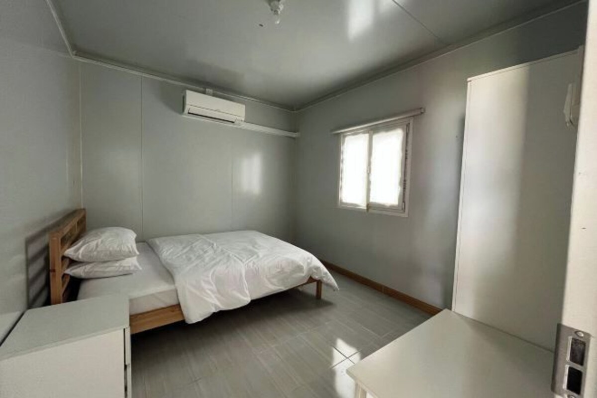Een slaapkamer met een bed, een kledingkast, een bureau en een raam.