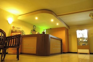 Un área de recepción con un mostrador de madera, un reloj y una vitrina de vidrio.