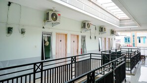 A corridor with multiple doors, air conditioning units, and a skylight. - Griya Safitri Syariah (Palembang)