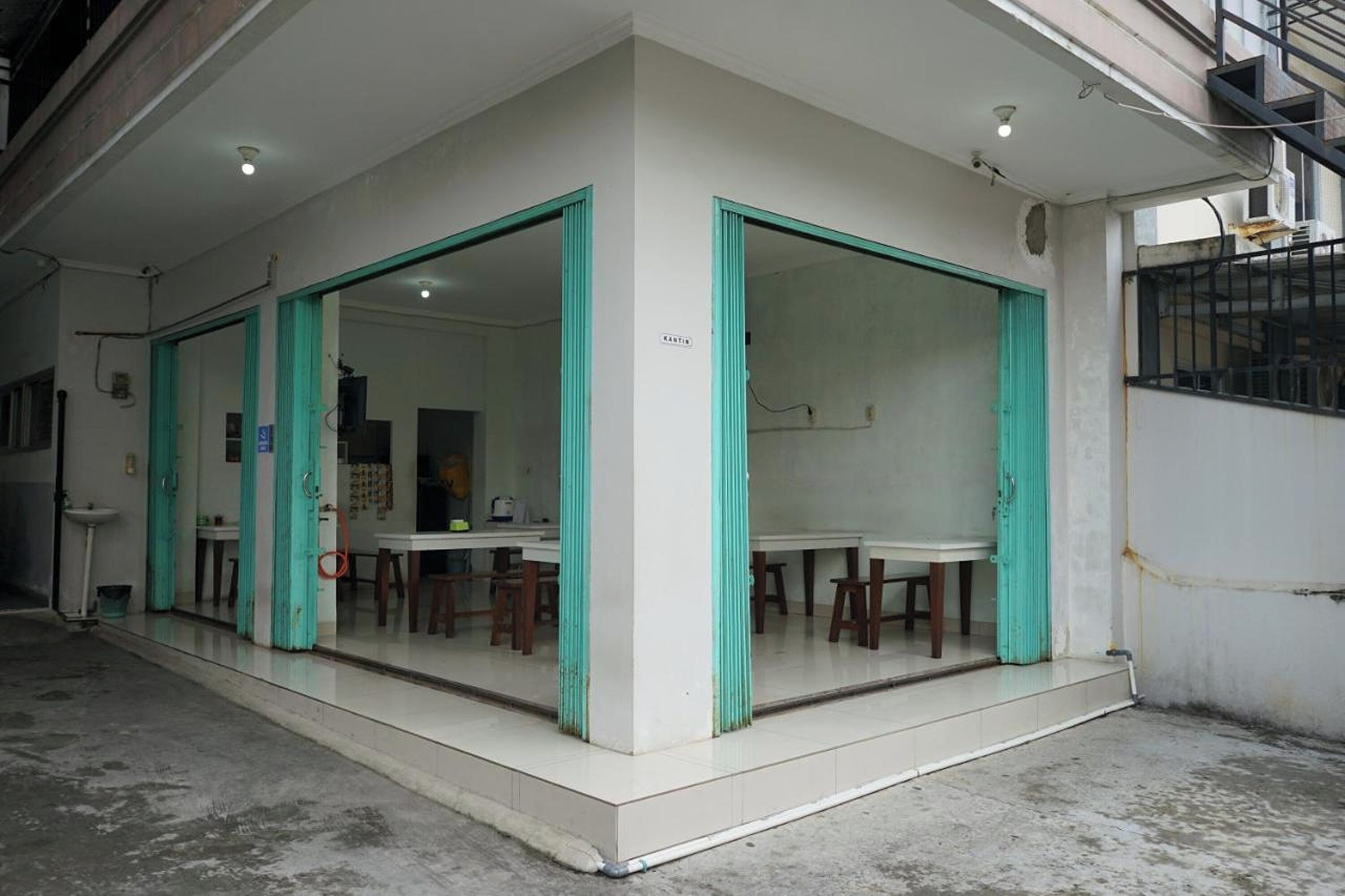 A room with a tiled floor, a white wall, and a window with a metal grill.