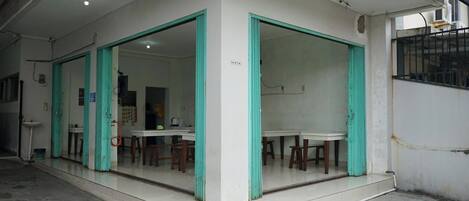 A room with a tiled floor, a white wall, and a window with a metal grill.
