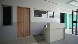 A reception area with a wooden door, a reception desk, and a window with blinds. - Griya Safitri Syariah (Palembang)