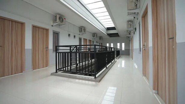 A corridor with wooden doors, a black railing, and a skylight. - Griya Safitri Syariah (Palembang)