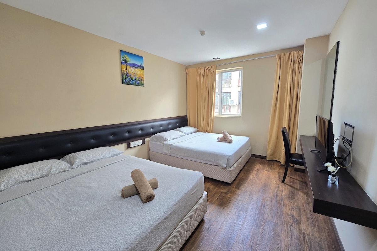 A hotel room with two beds, a painting on the wall, a window with curtains, a desk with a computer, and a TV.