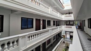 A multi-level hotel with white exterior walls, balconies with balustrades, and large windows. - Benediktus Pilgerhaus Inn (Vigan)
