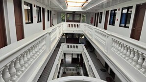 A multi-level corridor with white balustrades and doors, leading to balconies with potted plants. - Benediktus Pilgerhaus Inn (Vigan)